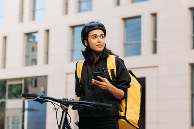 Portrait of young woman standing against building