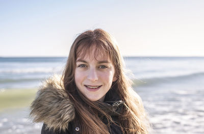 Portrait of smiling young woman against sea