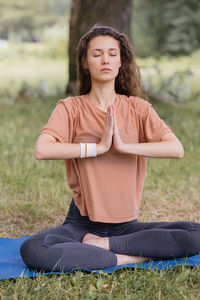 Woman with curly hair meditates in a park. yoga and meditation for mental and physical health