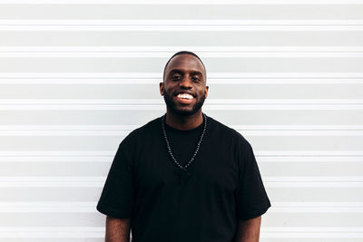 Happy black man posing and smiling over white background and looking at camera