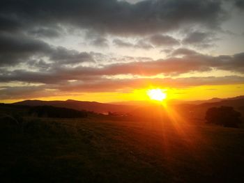 Scenic view of silhouette field against sky during sunset