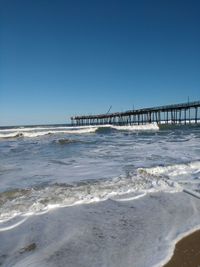 Bridge over calm sea against clear sky