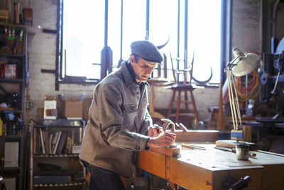 Confident carpenter planning wood on table in workshop