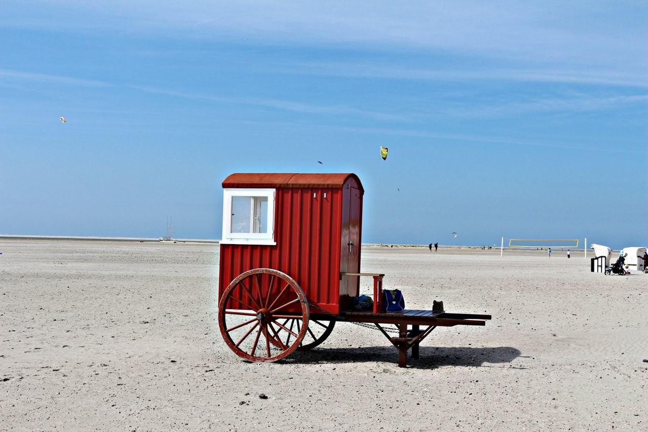 sand, beach, sky, transportation, blue, built structure, sea, architecture, bicycle, shore, land vehicle, building exterior, day, sunlight, outdoors, mode of transport, tranquility, absence, incidental people, tranquil scene