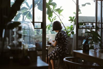 Side view of young woman looking through window