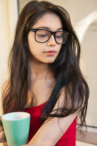Young woman holding coffee cup looking down