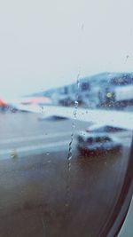 Close-up of water drops on airplane against sky