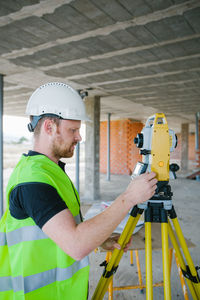 Surveyor engineer working at construction site with measuring equipment (total station)