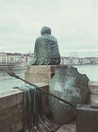 Rear view of statue by sea against sky