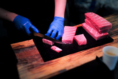 Selective focus on the hands of chef cutting the meat of tuna on the cutting board