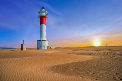 Low angle view of lighthouse against sky at sunset