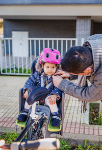 Father adjusting cycling helmet for daughter in park