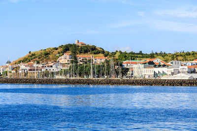 Houses by sea against sky in town