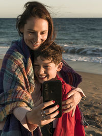 Mother and son doing selfie while standing at beach