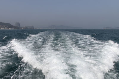 Scenic view of wake in sea against clear sky