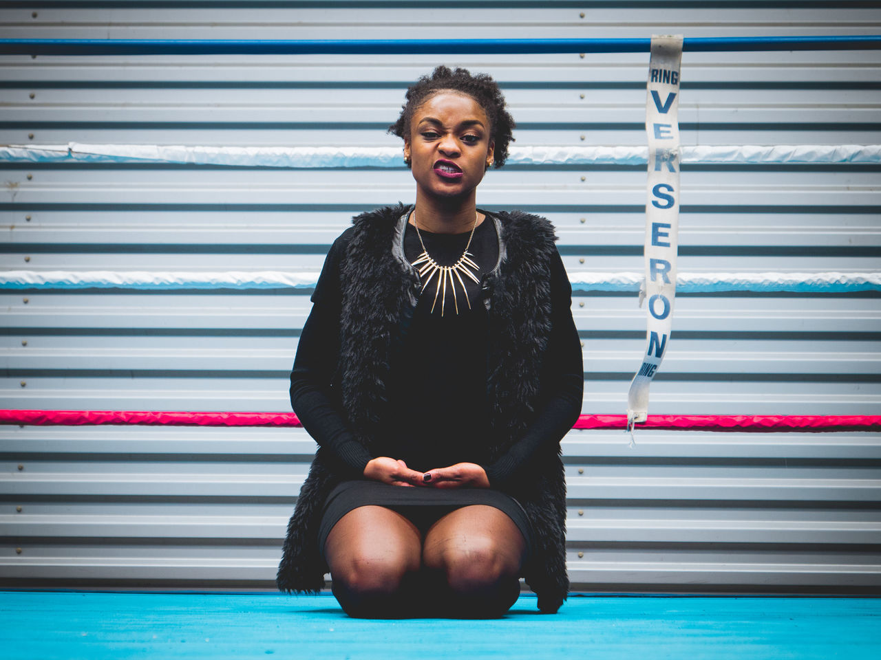 front view, young adult, one person, young women, real people, leisure activity, jacket, happiness, lifestyles, full length, sitting, smiling, day, looking at camera, corrugated iron, outdoors, beautiful woman, people