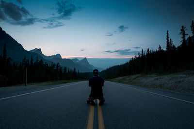 Sunset on the icefields parkway. a man kneels in the road to capture the perfect shot.