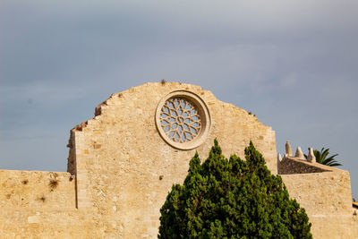 Low angle view of cross on building against sky