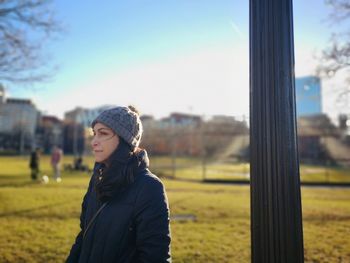 Portrait of young woman standing on field against sky during winter