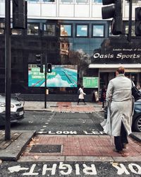 Rear view of people walking on street in city