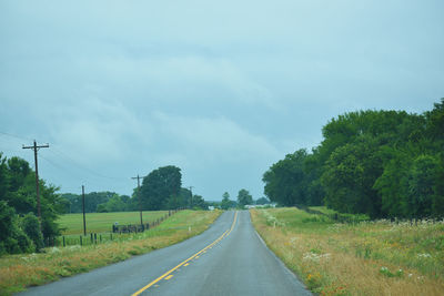 Road amidst trees against sky