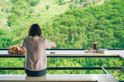 Rear view of woman sitting on table