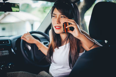 Young woman using mobile phone in car