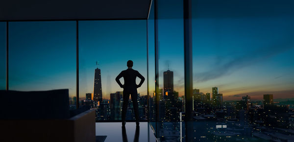 Rear view of silhouette man standing by buildings against sky