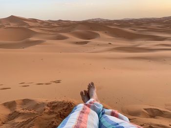 Low section of woman relaxing on sand at beach