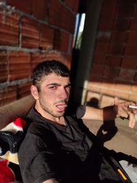 Portrait of young man standing against brick wall