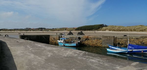 Boats moored at harbor against sky