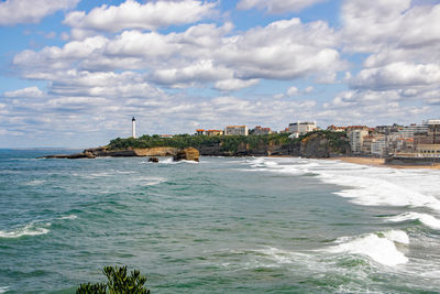 Scenic view of sea by buildings against sky