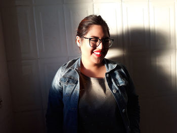 Portrait of smiling young woman standing against wall