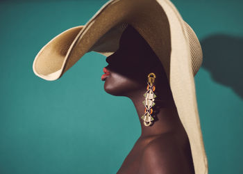 Close-up of woman wearing hat against blue background
