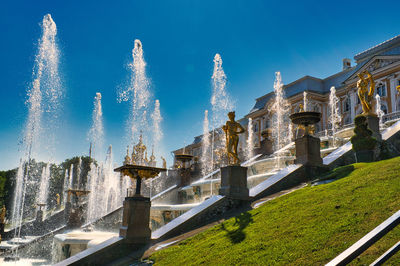 Fountain in front of building against blue sky