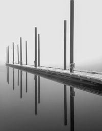 Wooden posts in lake against sky