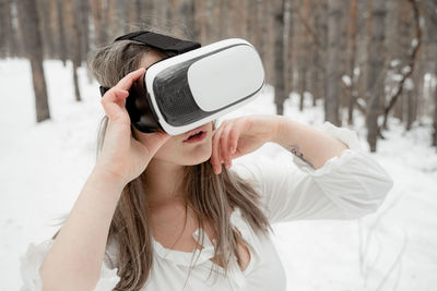 Woman wearing virtual reality simulator against trees outdoors