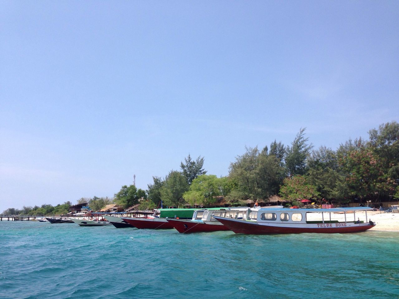 water, nautical vessel, boat, transportation, tree, clear sky, waterfront, mode of transport, sea, blue, tranquil scene, tranquility, copy space, scenics, moored, nature, beauty in nature, travel, day, incidental people