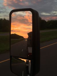 Cars on road against sky during sunset