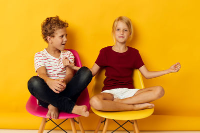 Portrait of happy friends using mobile phone while sitting on sofa at home