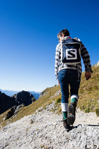 Man standing on mountain road against clear blue sky