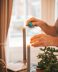 Cropped hand of man igniting candle at home
