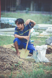 Side view of young man sitting on field