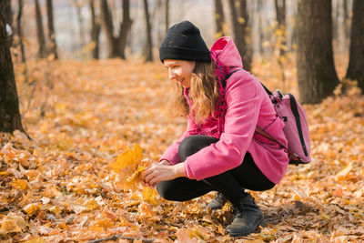 Side view of woman sitting on tree trunk