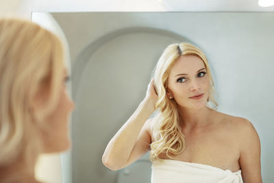 Beautiful woman looking in mirror at home