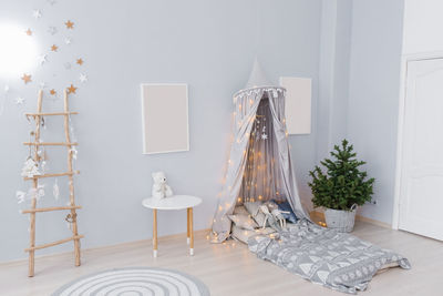 Cute christmas baby room decor in blue colors. a bed with an awning, a tree in a pot, mockups 