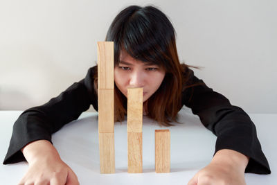 Businesswoman looking at stacked wooden blocks over table