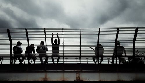 People on railing against sky