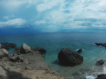 Rocks by sea against blue sky