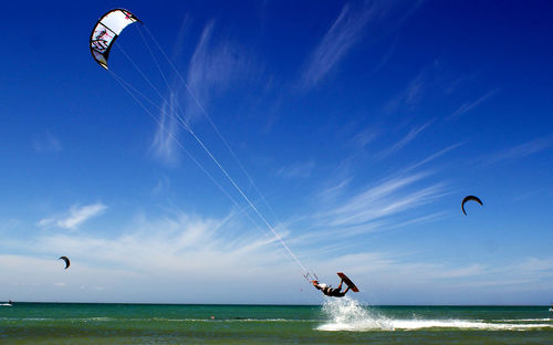 People paragliding over sea against sky